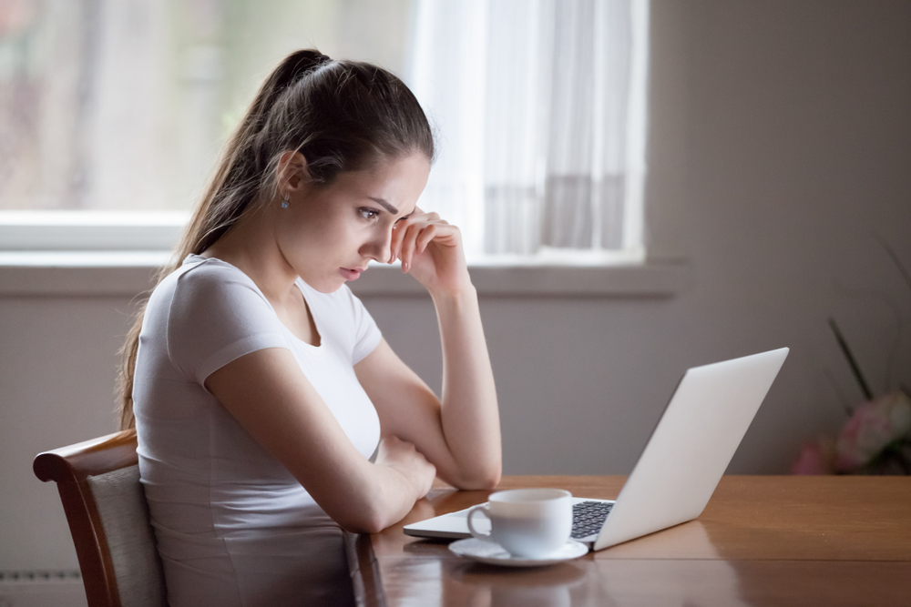 MUJER JOVEN FRENTE A COMPUTADORA TRABAJO A DISTANCIA REMOTO HOME OFFICE CAUSAS DE HEMORROIDES PANDEMIA POCA ACTIVIDAD FÍSICA